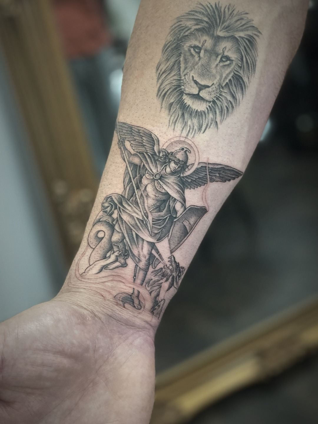 Archangel Michael with spear beneath a lion, forearm tattoo, black and grey by Matt Roe, Kensington London