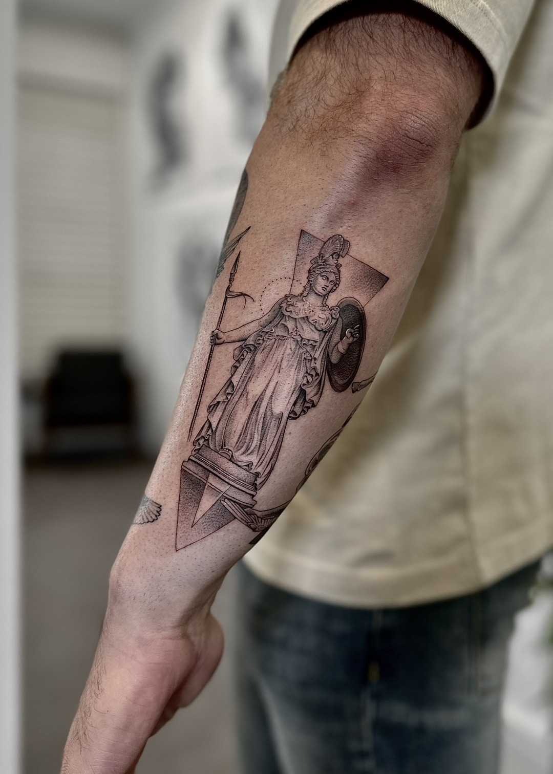 Athena goddess with spear and shield geometric forearm tattoo, black and grey by Matt Roe, Kensington London
