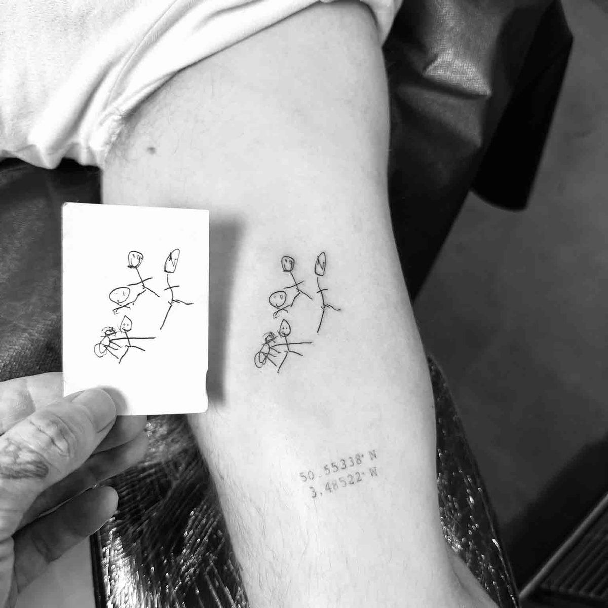 Child's drawing stick figures tattoo with GPS coordinates on forearm by Matt Roe, Kensington London