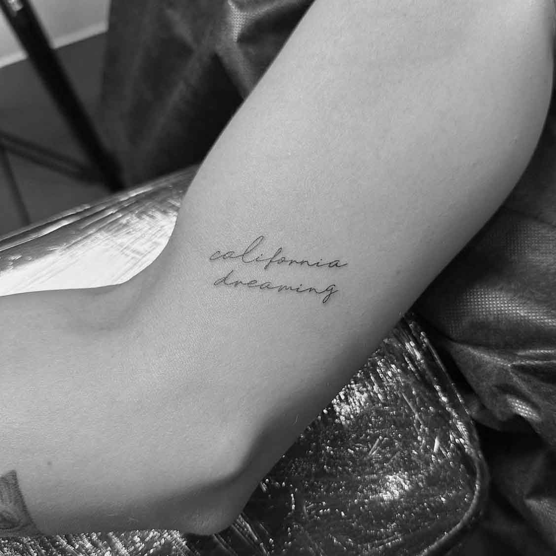 Delicate cursive script word tattoo on arm by Matt Roe, London