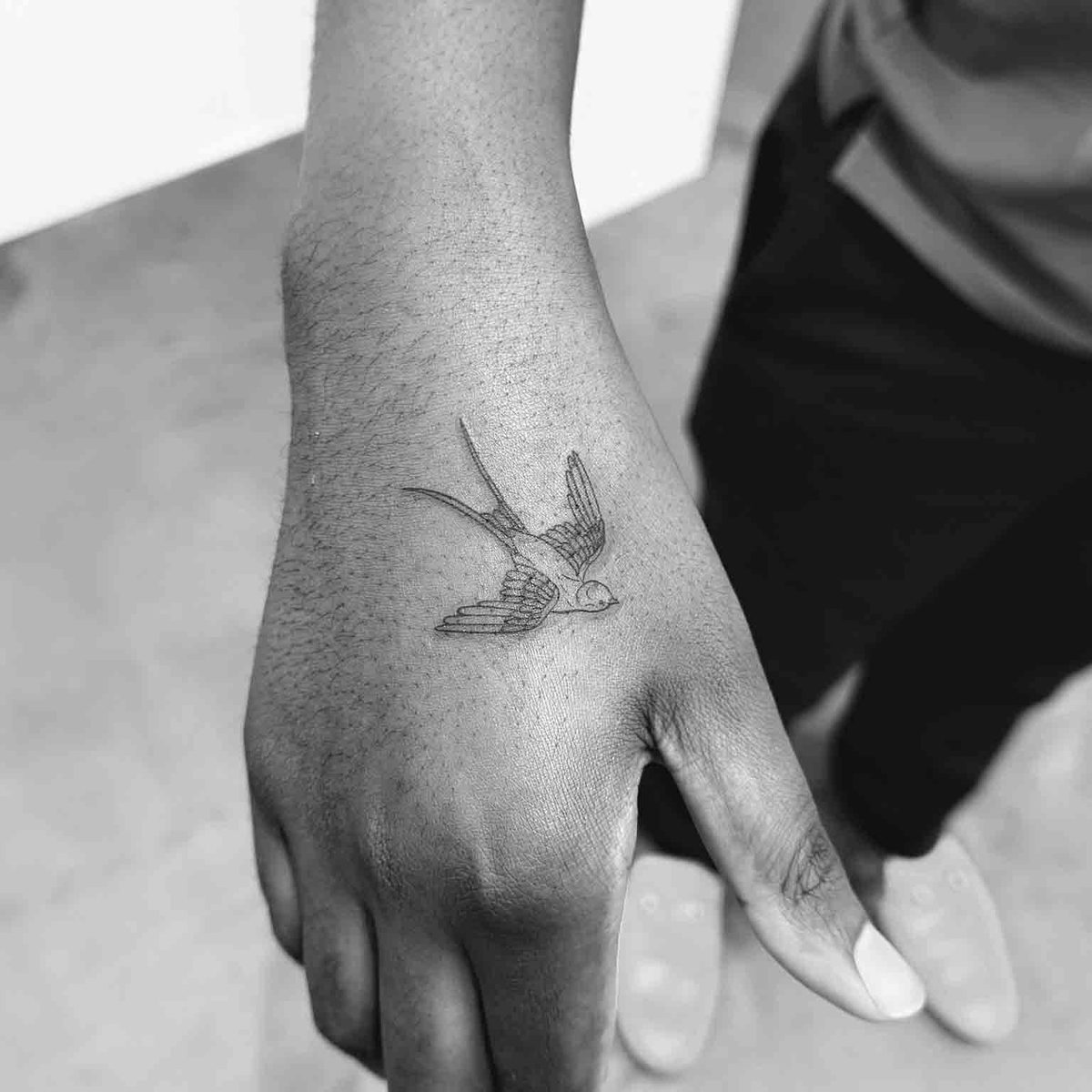 Fine line swallow bird tattoo on hand by Matt Roe, London