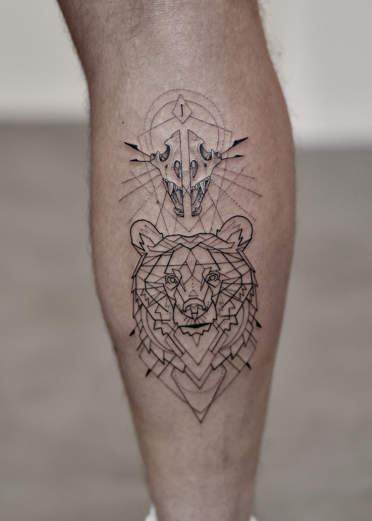 Geometric bear and skull calf tattoo, black and grey by Matt Roe, Kensington London