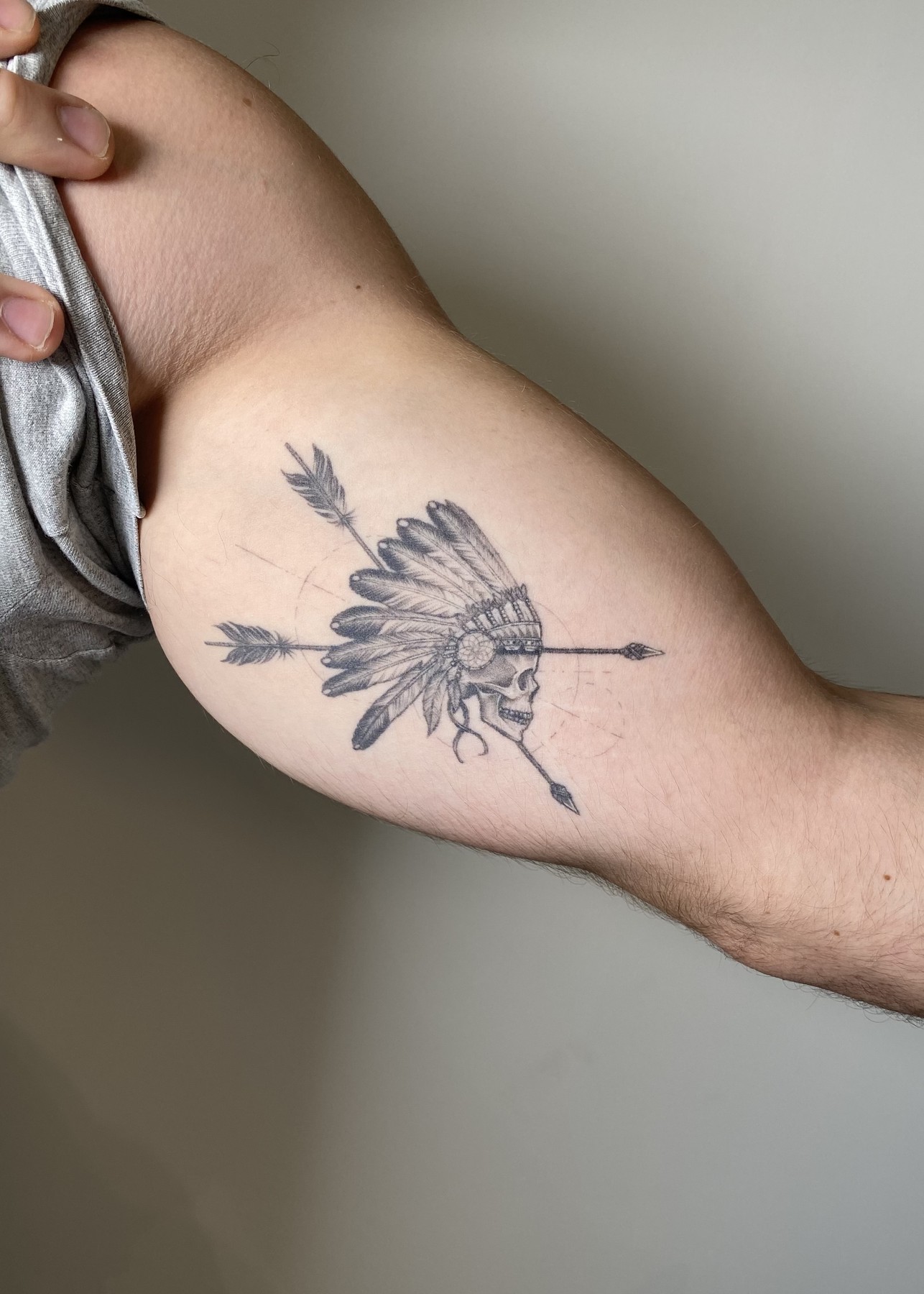 Healed skull with feathered headdress and arrows inner arm tattoo, black and grey by Matt Roe, Kensington London