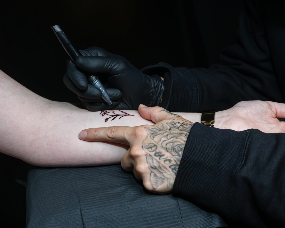 Fine line floral wrist tattoo in progress by Matt Roe