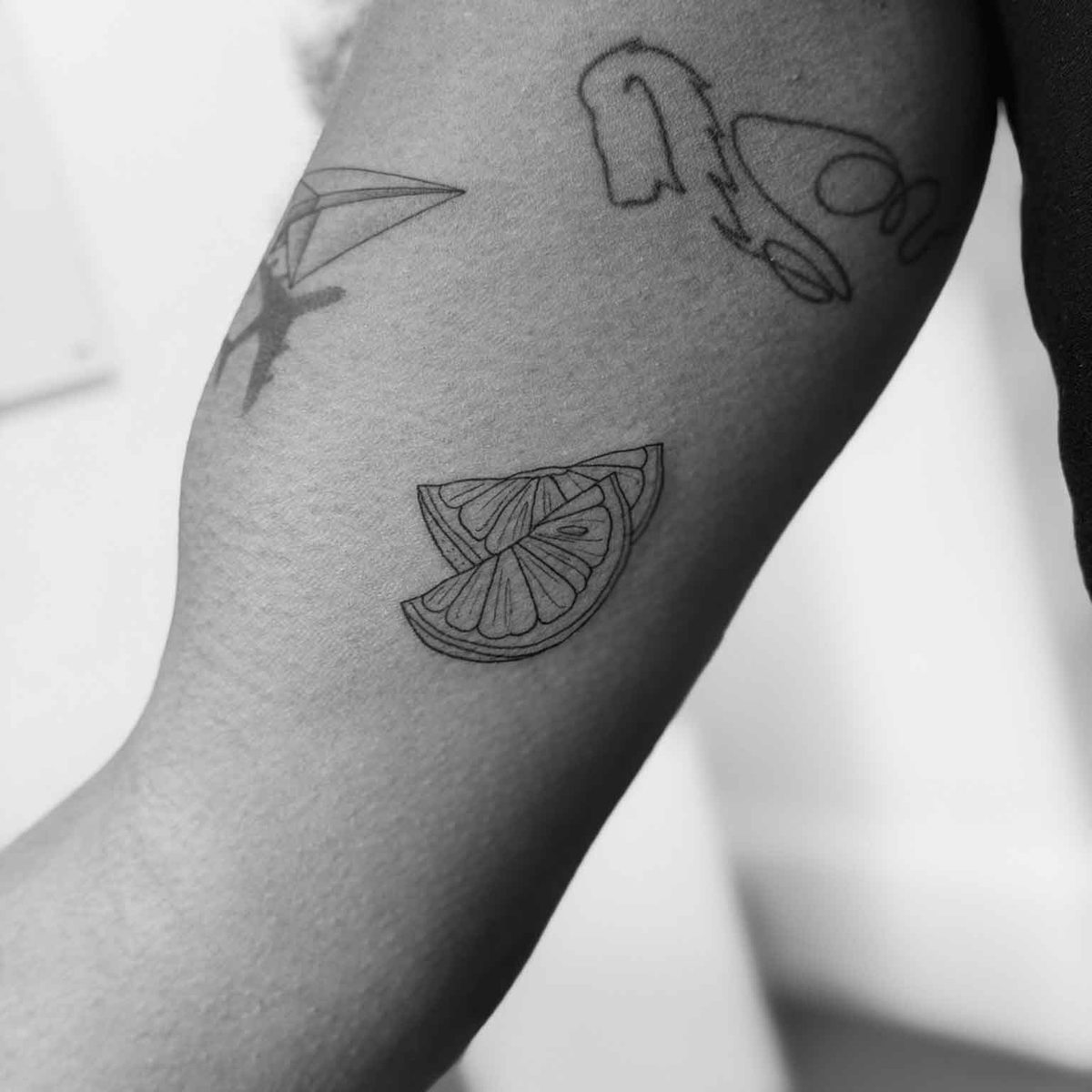 Small fine line lemon slice tattoo with mixed small pieces on arm by Matt Roe, Kensington London