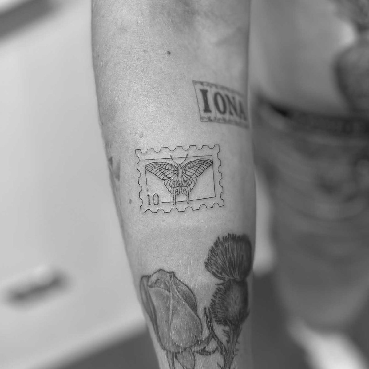 Fine line postage stamp with moth tattoo on forearm by Matt Roe, Kensington London