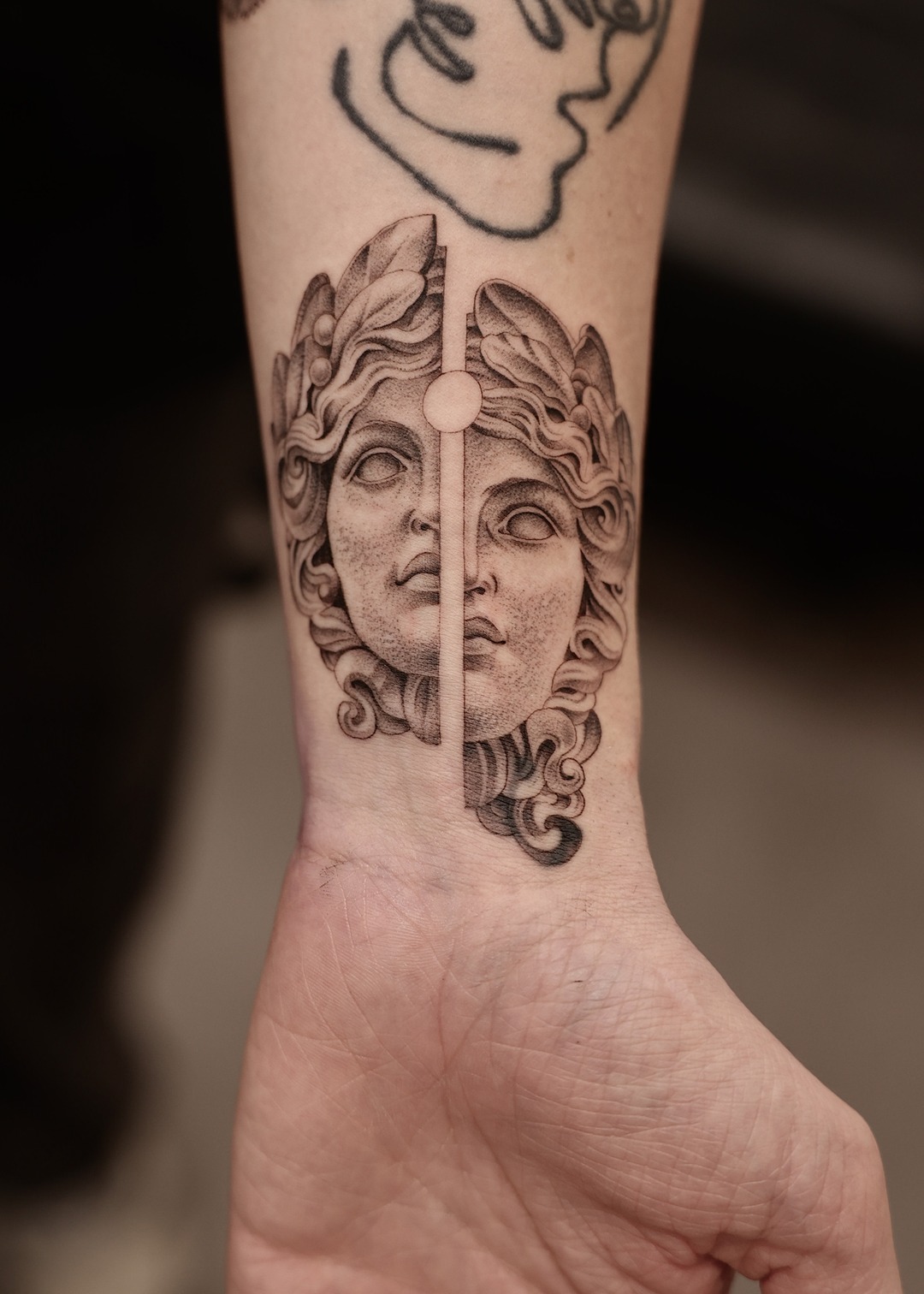 Split Greek goddess face wrist tattoo, black and grey by Matt Roe, Kensington London