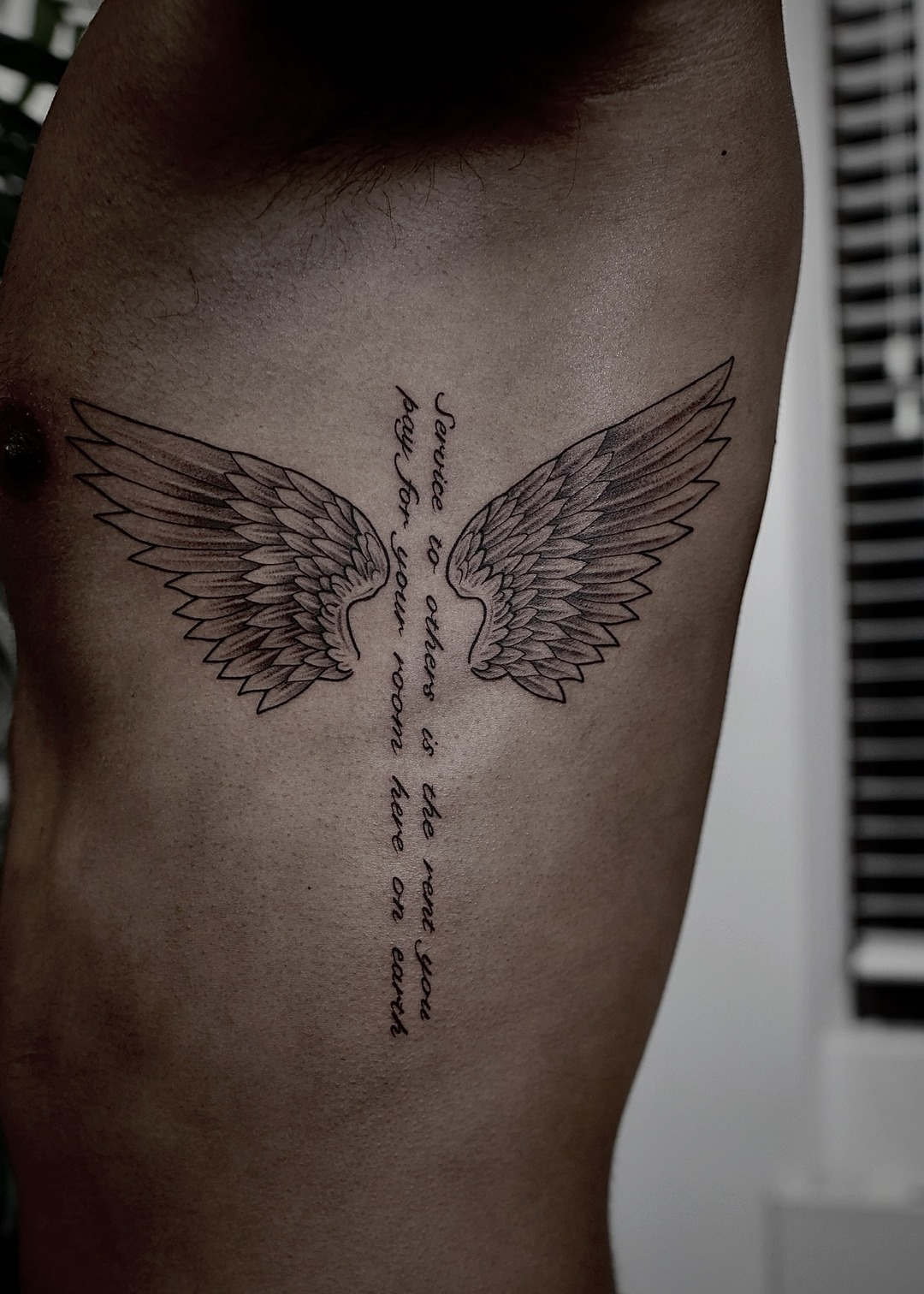 Spread wings with script down the sternum, chest tattoo, black and grey by Matt Roe, Kensington London