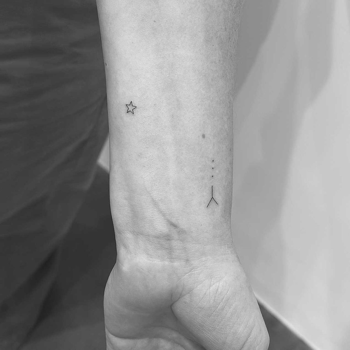 Tiny fine line star and minimalist symbol tattoo on wrist by Matt Roe, London