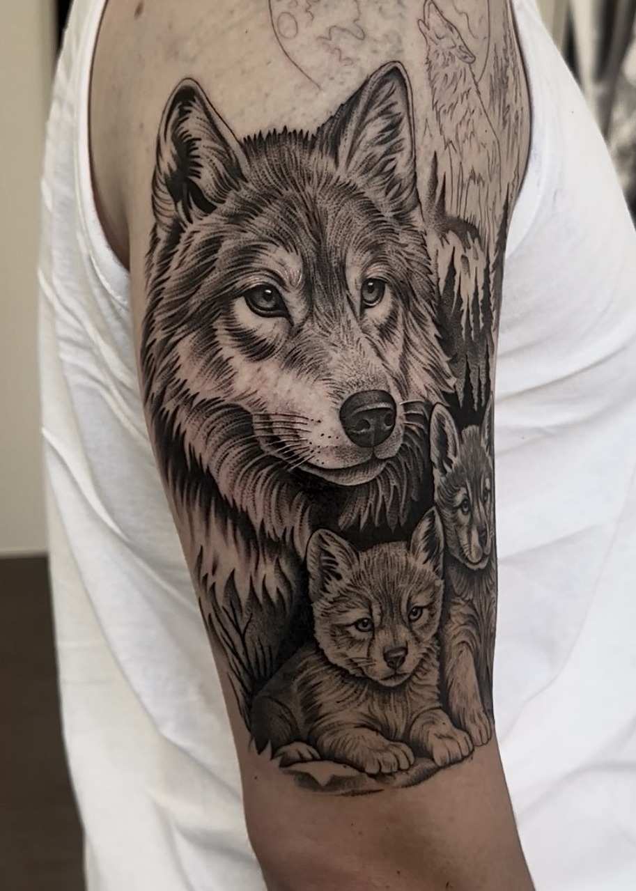 Wolf family with cubs and moon upper arm tattoo, black and grey by Matt Roe, Kensington London